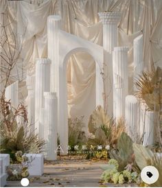 an outdoor ceremony with white columns and greenery on the side, surrounded by drapes