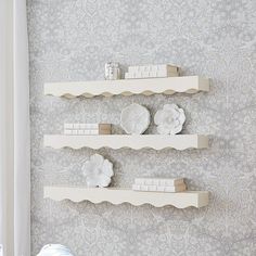 three white shelves are mounted on the wall