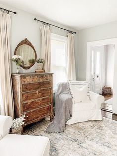 a living room filled with furniture and a mirror on top of a chest of drawers