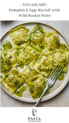 a white plate topped with ravioli and broccoli covered in pesto next to a fork