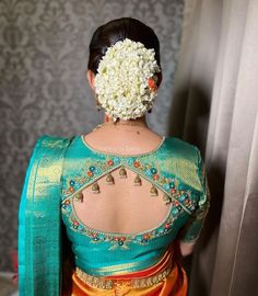 the back of a woman's head with flowers in her hair and an orange skirt