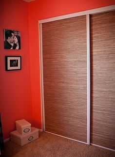 an orange room with two sliding doors and pictures on the wall above it, along with a cardboard box