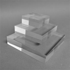 three stacks of clear acrylic blocks sitting on top of each other in front of a gray background