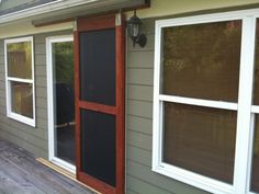 a house with two windows and a screen door on the side of the house that is closed