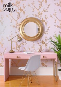 a pink desk with a mirror on it and a plant in the corner next to it