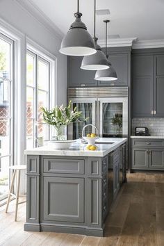 an image of a kitchen with gray cabinets and white counter tops on the left side