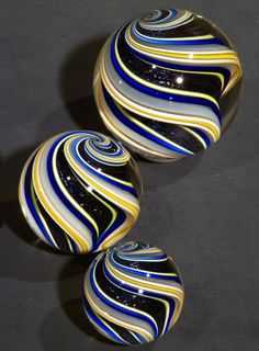 two marbles sitting next to each other on top of a black surface with blue, yellow and white stripes