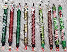 six christmas themed pens lined up on a white table with the numbers 1, 2, 4, and 5