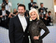 a man and woman standing next to each other on a red carpet with cameras in the background