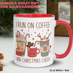 a red and white coffee mug sitting on top of a table next to a cookie