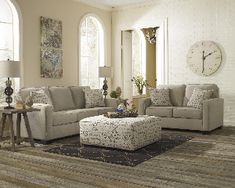 a living room filled with furniture and a clock on the wall above it's windows