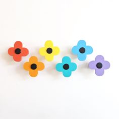 six flower shaped magnets sitting next to each other on a white surface with black dots