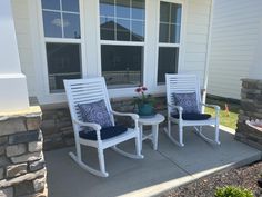 two white rocking chairs sitting on top of a patio