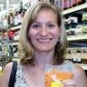 a woman holding up a piece of fruit in front of a store shelf with other items on the shelves