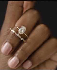 a woman's hand holding an engagement ring with two diamonds on the top and bottom