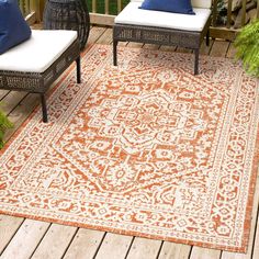 an orange and white rug on a wooden deck with two wicker chairs next to it