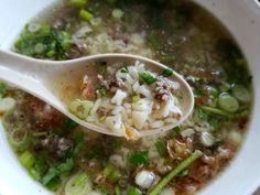 a spoon full of soup with noodles, meat and veggies in it on a table