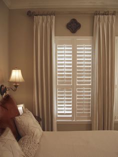 a bed sitting under a window next to a lamp