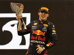 a man holding up a trophy on top of a race car podium in front of a red bull sign