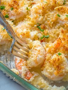 a glass casserole dish filled with shrimp and grits, garnished with parsley