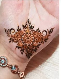 a woman's hand with a henna tattoo on her left wrist and an intricate design