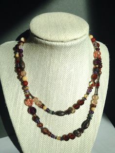 "30 inch necklace. Austrian crystal and Czechoslovakian glass in shades of smoke topaz, amethyst, and light peach. Tiger Jasper semi-precious gemstone accents. Many of the beads are rare and irreplaceable, circa 1920-1930. Trim is antiqued bronze, from our own tooling. \"Rinky Dinky Parlez-Vous\" necklace is handmade in the USA. Owen Glass Collection jewelry is ready for gift-giving, with an organza bag and description card included. Please let us know if you would like us to make a matching bra Art Deco Necklace, Light Peach, Matching Bracelets, Austrian Crystal, Metallic Accents, Organza Bags, Earth Tones, Semi Precious Gemstones, Glass Collection