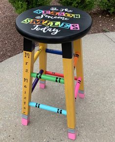 a child's stool made out of crayons with writing on the seat