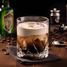 a glass filled with liquid and ice sitting on top of a wooden table