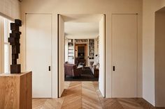 an open door leading to a living room with wooden floors and white walls in the background