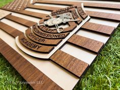 a wooden plaque with the words and emblems on it sitting in the green grass