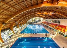 an indoor swimming pool in the middle of a building with lots of windows and wooden ceilinging