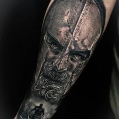 a man's arm with a black and grey tattoo on it, depicting the face of jesus