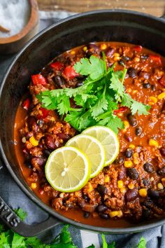 a skillet filled with chili and limes