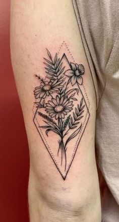 a black and white flower tattoo on the right arm, with an arrow in the middle