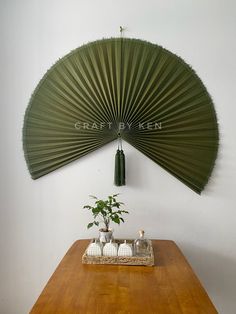 a wooden table topped with a green fan next to a potted plant on top of it