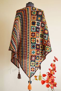 a crocheted shawl with tassels hanging from it