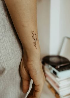 a small flower tattoo on the left wrist