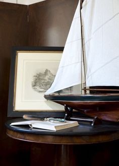 a small sailboat is sitting on a table next to a framed photo and books