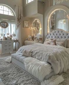 a white bedroom with lots of furniture and mirrors on the wall, along with an ottoman bed