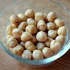 a glass bowl filled with chickpeas on top of a wooden table