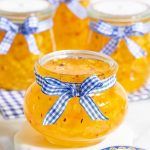 several jars filled with yellow colored food on top of a white tablecloth covered table