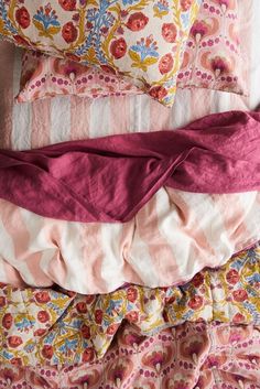 four pillows stacked on top of each other with pink and yellow sheets in the background