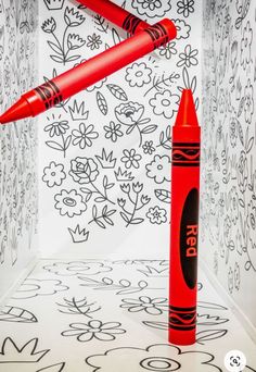 two red pens sitting on top of each other in front of a flowered wall