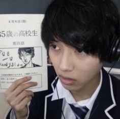 a young man wearing headphones holding up a book