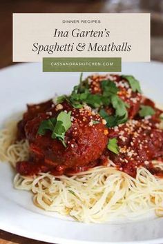 spaghetti and meatballs on a white plate with green garnish in the middle