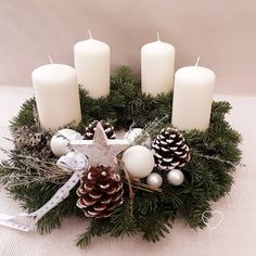 a wreath with pine cones and candles on it is sitting next to other christmas decorations