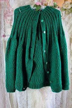 a green cardigan sweater hanging on a mannequin