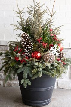 a potted plant with pine cones, berries and evergreens in it is sitting on the ground