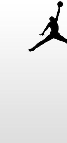 the silhouette of a basketball player jumping in the air to dunk at a ball