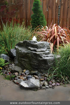 an outdoor fountain surrounded by rocks and plants